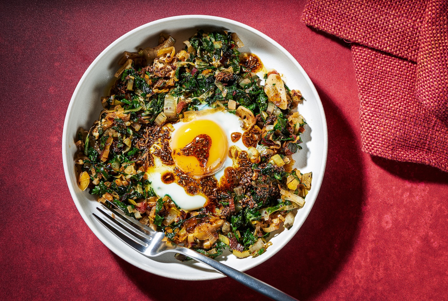 Ces œufs au four aux poireaux et aux blettes présentent un tadka grésillant et épicé